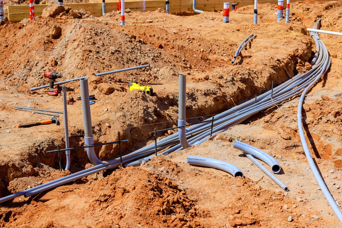 Conduit and utility duct bank being laid in an open trench in southern red dirt